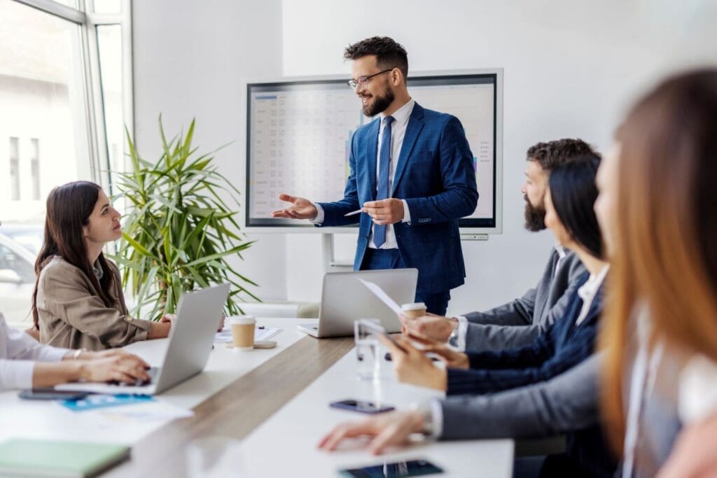 Corporate leader speaking supportively with employees, illustrating psychological safety and trust-based leadership training by Ginny Estupinian, PhD